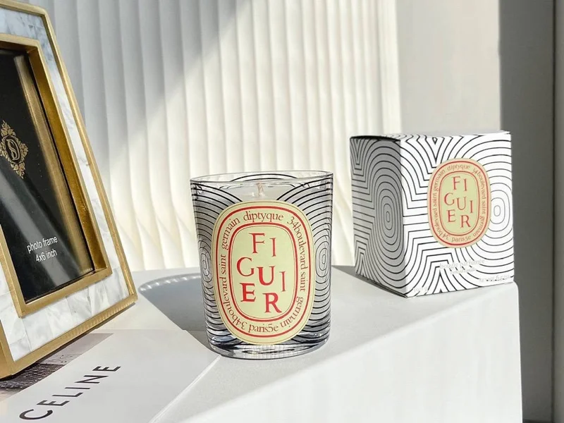 Diptyque Figuier candle burning with a soft glow, symbolizing the Mediterranean fig tree fragrance and natural inspiration.