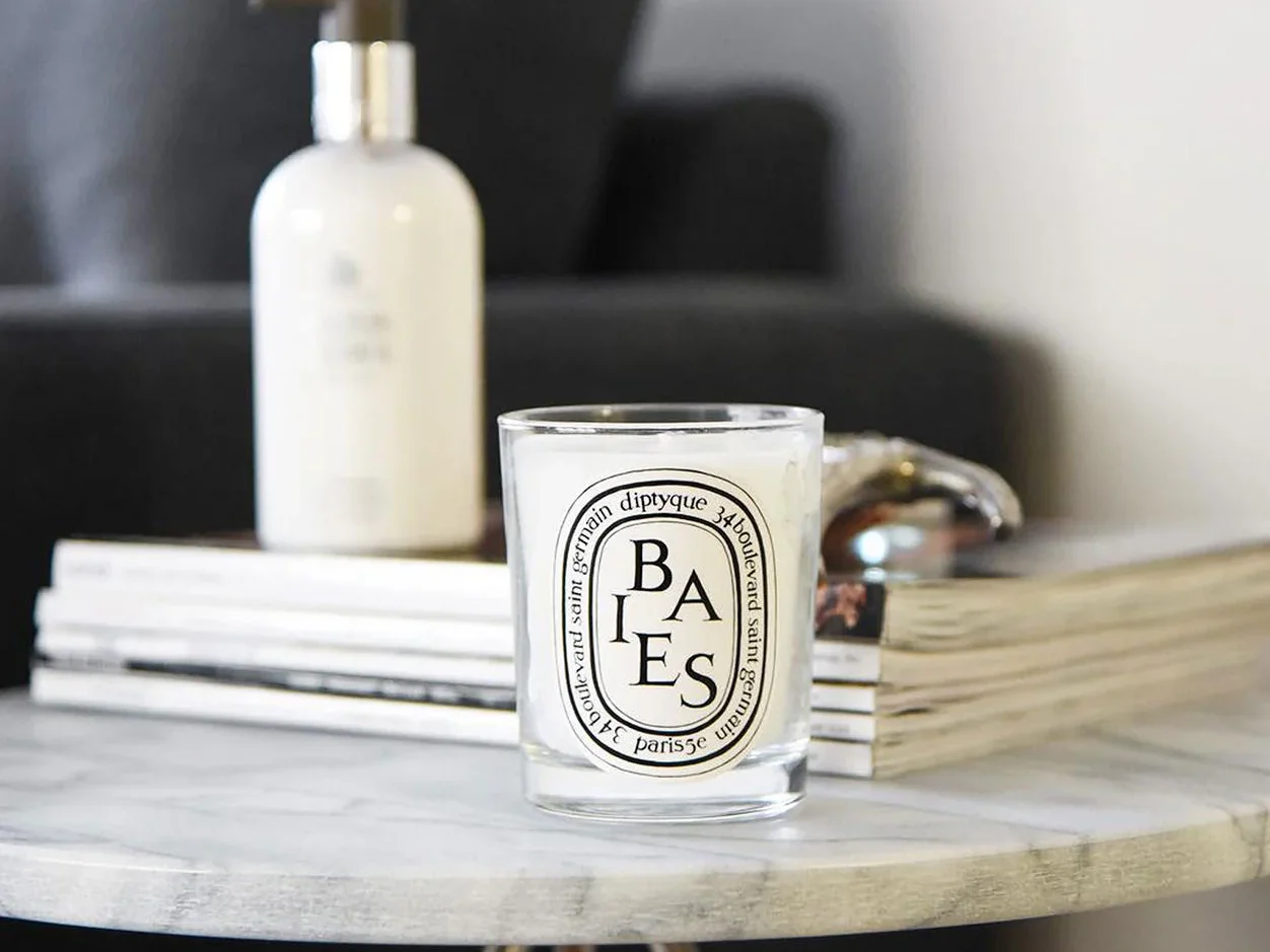 Diptyque Baies candle placed on a coffee table, illustrating the craftsmanship and luxury of its design.