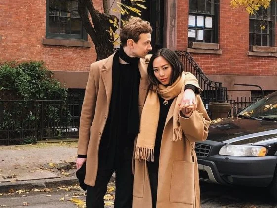 A young couple dressed in fall attire, representing the gender-neutral appeal of Eau Duelle by Diptyque, a unisex fragrance with vanilla and spice