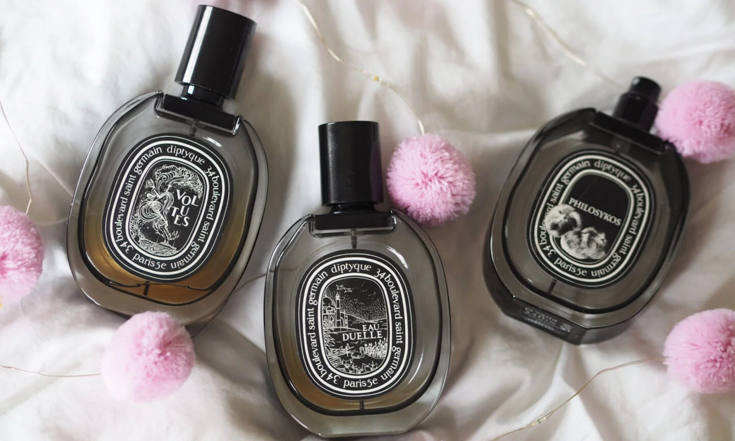 Three Diptyque perfume bottles elegantly displayed on a textured surface, representing the brand’s luxurious essence.