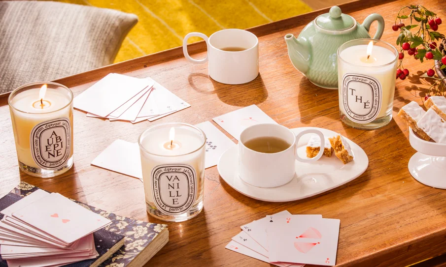 Diptyque’s luxurious candles and perfumes displayed on a dark wooden surface.