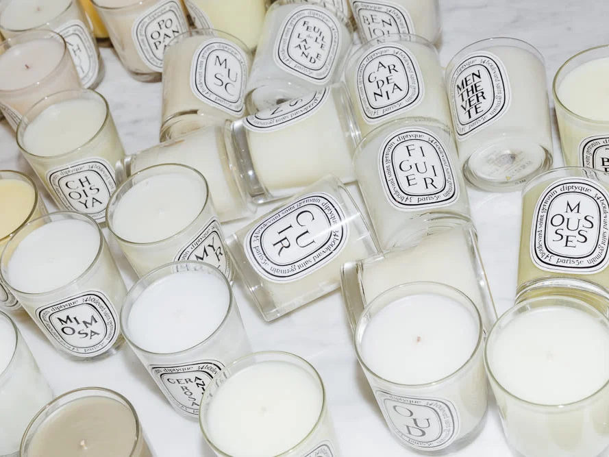 Assorted Diptyque candles in a cozy setting, summarizing top candle choices for luxurious ambiance