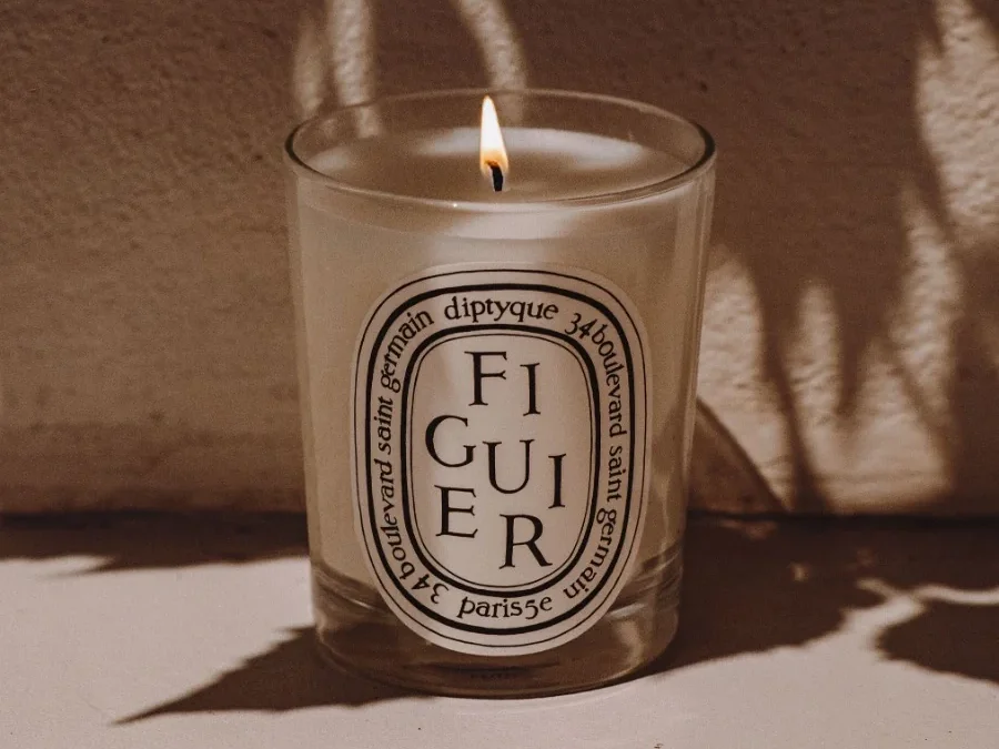 Close-up of the Diptyque Figuier candle emitting a soft glow, highlighting its fig tree fragrance with notes of fig leaves and creamy fig milk.